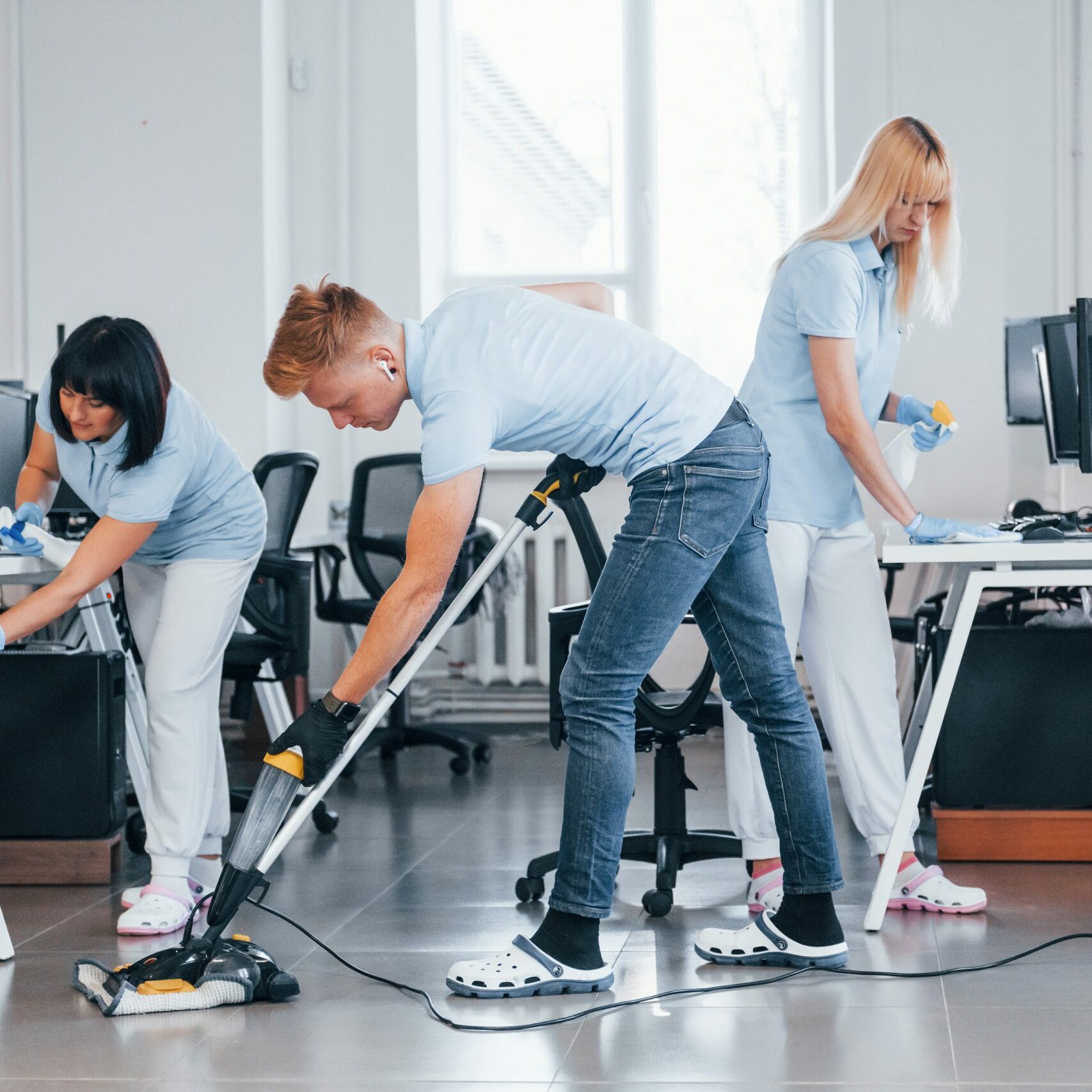 Concentrated at job. Group of workers clean modern office together at daytime.